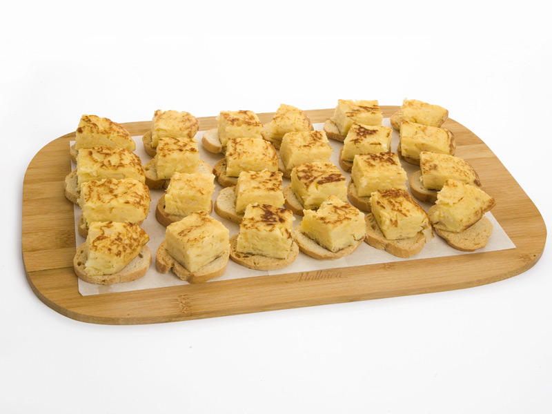 Tortilla española recién hecha sobre tostas en tabla de madera Tortilla española recién hecha sobre tostas en tabla de madera